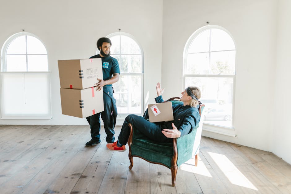 A professional removal technician from Removal Companies Stockwell is inside a bright, spacious room with light-colored wooden flooring and two large arched windows allowing natural light to fill the 